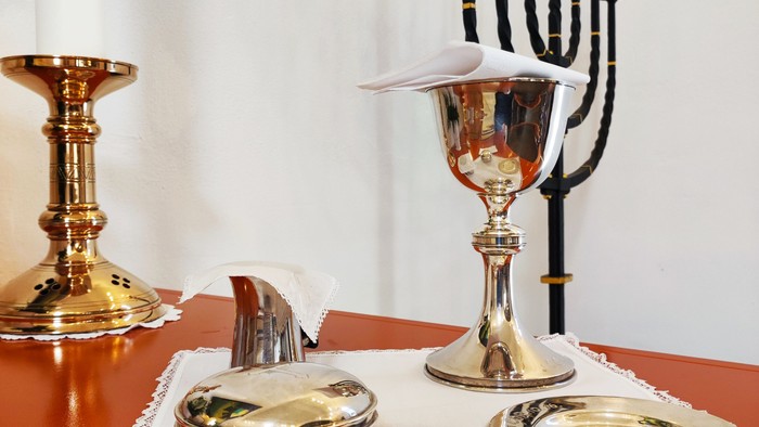 Elegant hanukkah-opstilling med en menorah, bæger, lysestager og dekorativt service på en rød dug.