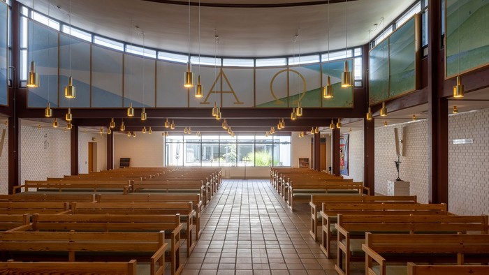 En moderne kirkeindretning med træbænke og hængende lygter