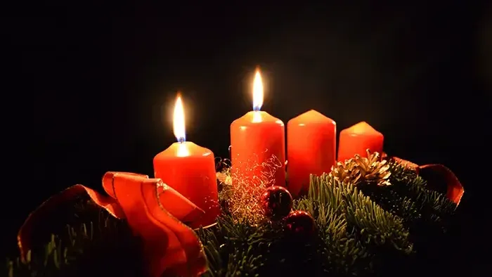 Vier brennende Kerzen auf Adventskranz im Dunkeln