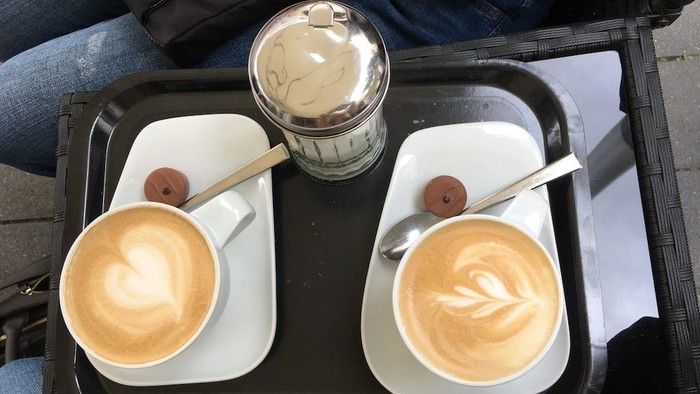 Zwei Kaffeetassen mit Milchschaum auf Tablett