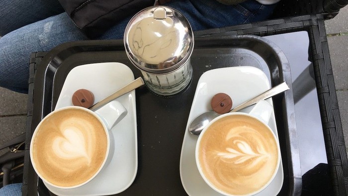 Zwei Kaffeetassen mit Milchschaum auf Tablett