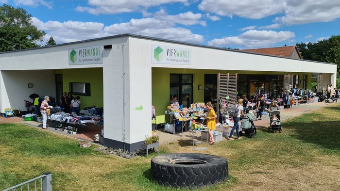 Ein weißes Gebäude mit grünem Dach, auf dem "Fleischhauer" steht, mit Menschen und Fahrrädern davor