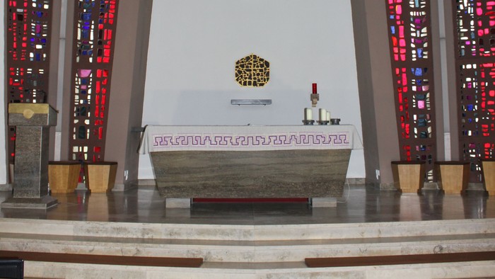 Die Kirche mit Altarraum, Kreuz und buntem Glasfenster