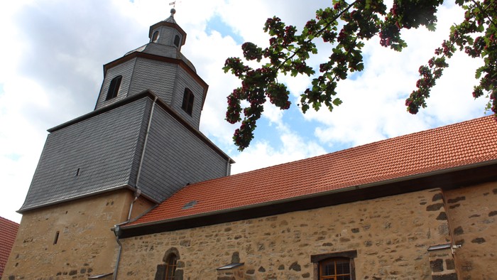 Steinkirche mit rotem Dach und Glockenturm.