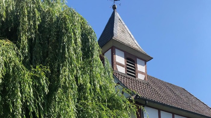 Menschen sitzen draußen vor einer Kirche mit einem Baum.