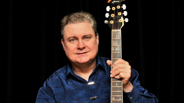 Mann in blauem Hemd hält rote E-Gitarre