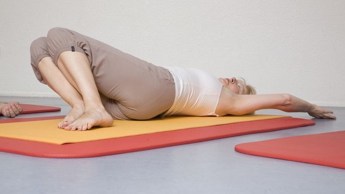 Frau übt Yoga auf einem gelben und roten Matte