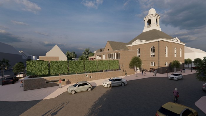 Das Bild zeigt eine Kirche mit einem Turm und Autos vor dem Gebäude.