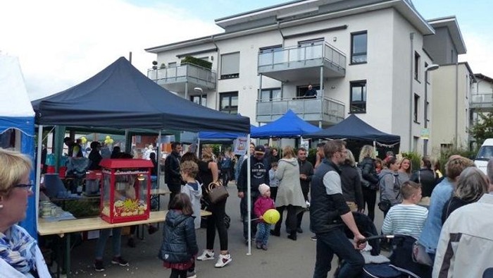 Markttag mit vielen Menschen und Ständen vor Wohngebäuden