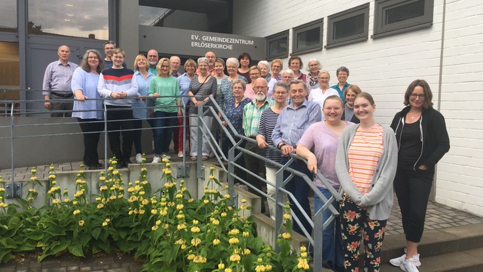 Ein Gruppenfoto vor einem Gebäude mit Treppe und Blumenbeeten