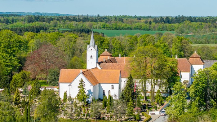 En lille landsby med kirke og huse omgivet af grønne skove og felter