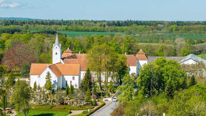 En lille landsby med kirke og huse omgivet af grønne skove og felter
