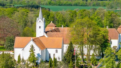 En lille landsby med kirke og huse omgivet af grønne skove og felter