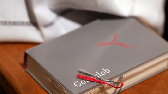 Ein Buch mit einem roten Lesebändchen und dem „Google“-Logo auf dem Cover, das auf einer Holzfläche liegt.