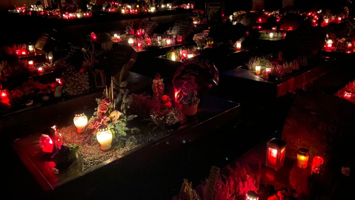 Viele brennende Kerzen auf Gräbern in der Nacht