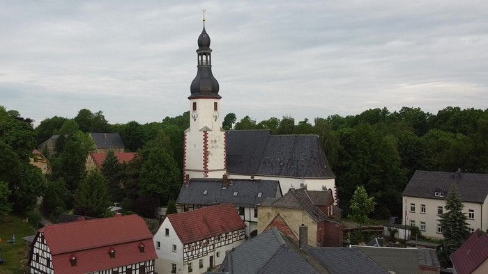 Ein Dorf mit einer Kirche und umgebenden Häusern, umgeben von Bäumen