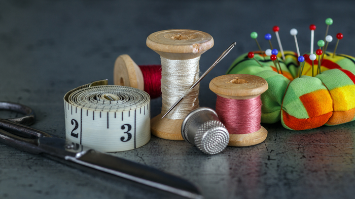 Billedet viser sy- og måleinstrumenter på en tæppe.