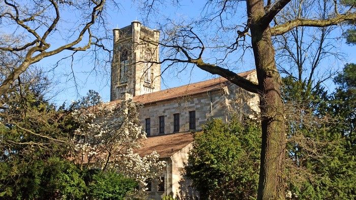 Großes Gebäude mit Turm, umgeben von Bäumen und einem Garten.