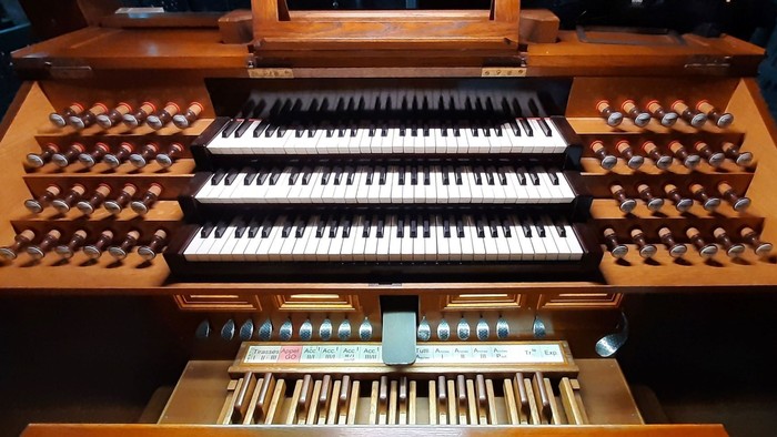 Clavier d'orgue avec multiples rangées de touches et boutons en bois.