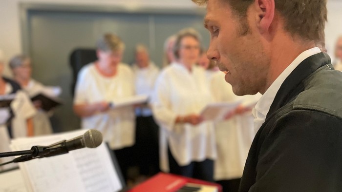 Mand spiller keyboard mens kor synger