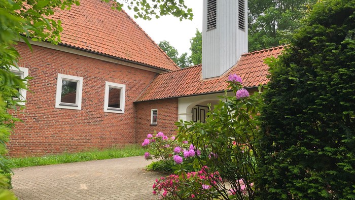 Das Bild zeigt ein rotes Backsteinhaus mit einem Ziegeldach und einem Schornstein.
