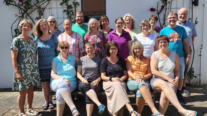 Eine Gruppe von Menschen posiert vor einem weißen Gebäude mit Rosen.