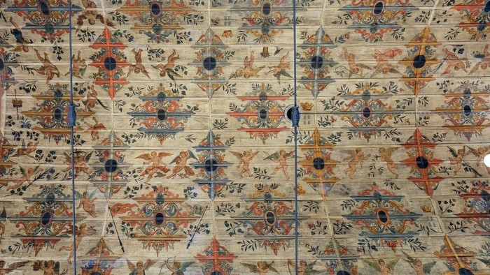 Die bemalte Decke der Kirche mit aufwendigen Mustern und Putten.