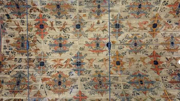 Die bemalte Decke der Kirche mit aufwendigen Mustern und Putten.