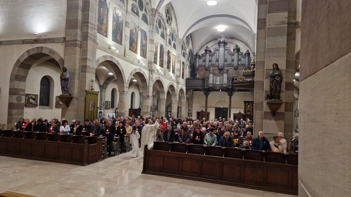 Une cérémonie religieuse en église avec de nombreux fidèles.