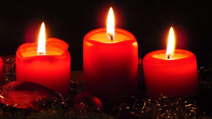 Drei brennende rote Kerzen auf dunklem Hintergrund