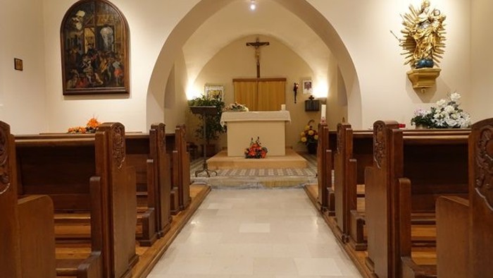 Intérieur d'église avec allée centrale, bancs en bois, et autel.
