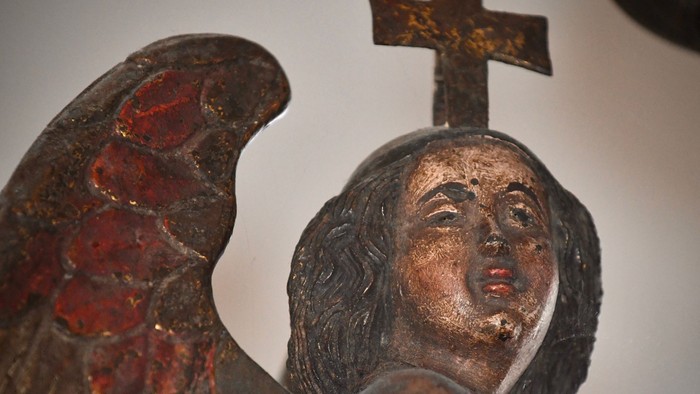 Engelstatue mit Kreuz, detaillierten Flügeln und sanftmütigem Ausdruck.