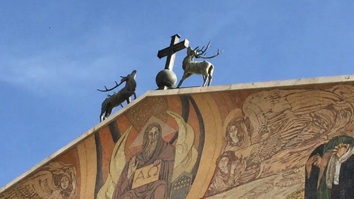 Zwei Stiere stehen auf einem Gebäude mit Mosaikdarstellungen.