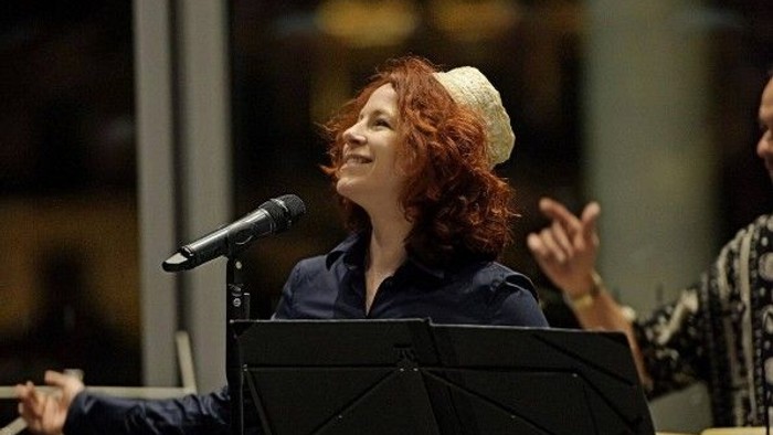 Eine Frau singt auf einer Bühne in ein Mikrofon.