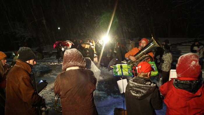 Gruppe von Menschen, die nachts im Freien versammelt sind, einige halten Geschenke.