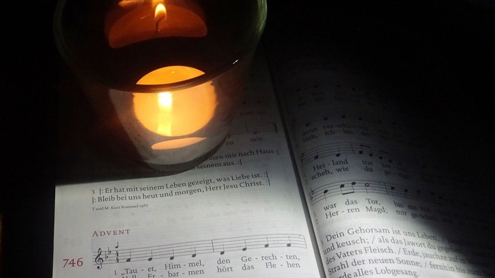 Kerze neben aufgeschlagenem Gesangbuch