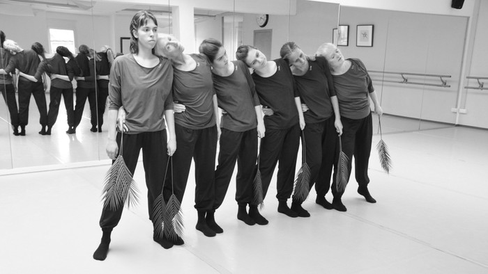 Sechs Frauen in tanzender Geste, aneinander gelehnt