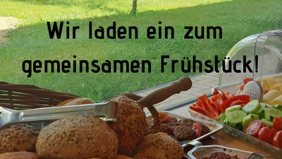 Ein Tisch mit verschiedenen Broten und Gemüsestücken, im Hintergrund ein Baum und ein Gebäude