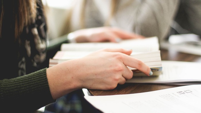 Eine Person tippt auf einem Laptop, umgeben von Papieren.