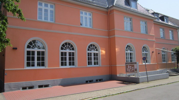 Ein oranges Gebäude mit weißen Fenstern und Dachgauben, das sich im Bau befindet.