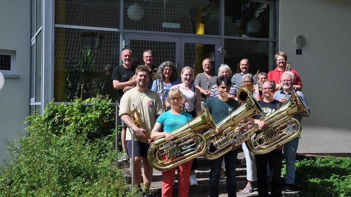 Eine Gruppe von Menschen posiert mit Musikinstrumenten vor einem Gebäude