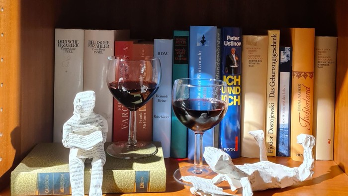 Bücherregal mit zwei Weingläsern und Papierzierfiguren