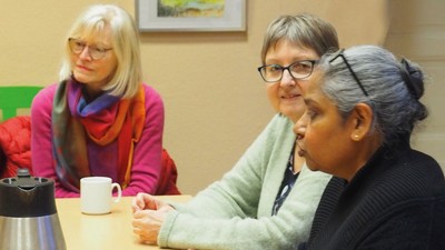 Drei Frauen sitzen an einem Tisch und unterhalten sich.