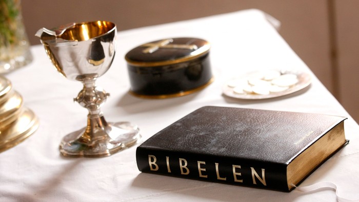 En skål, en boks og en bibel på bord med hvid duk