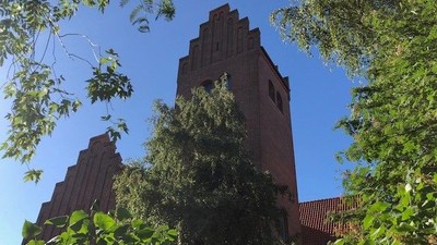 Tårn med røde teglsten og grønne træer foran