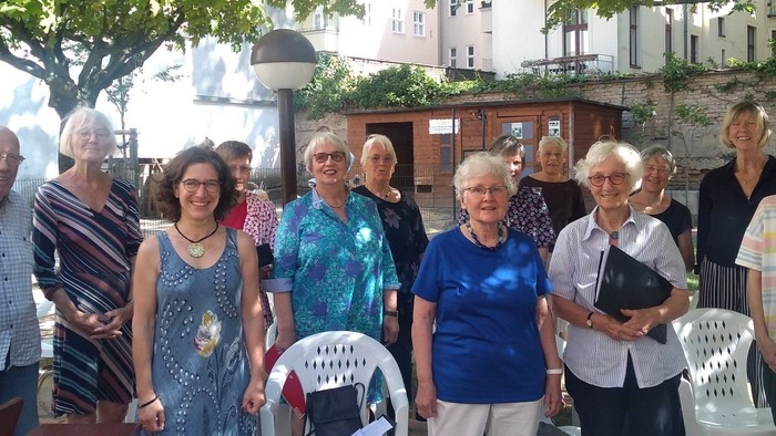 Eine Gruppe älterer Menschen steht im Freien und hält Stühle