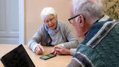 Ein älteres Paar schaut sich gemeinsam ein Smartphone an.