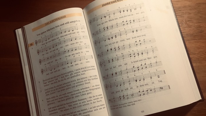 Offenes Buch mit Noten und Text auf einem Holztisch