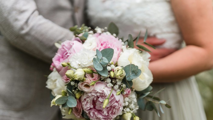 Eine Braut hält einen Strauß aus rosa und weißen Blumen.