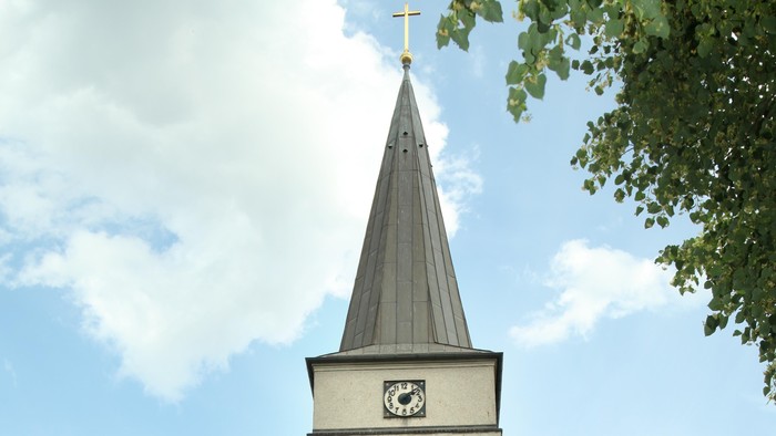 Weiße Kirche mit hohem Turm und Uhr.